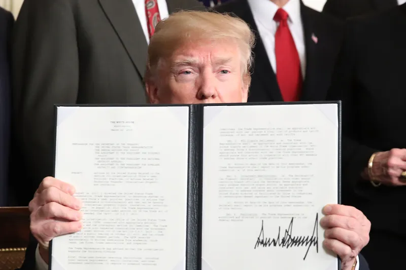 Trump peeks out from behind a two-page memo with his signature in large black ink.