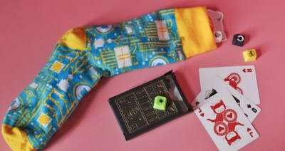 Yellow and blue sock with GitHub keycaps coming out the top and GitHub playing cards with Mona on a pink background.