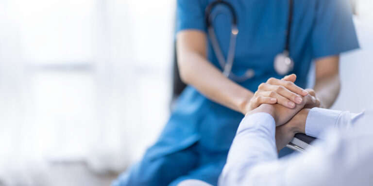 A physician holding a patient's hands