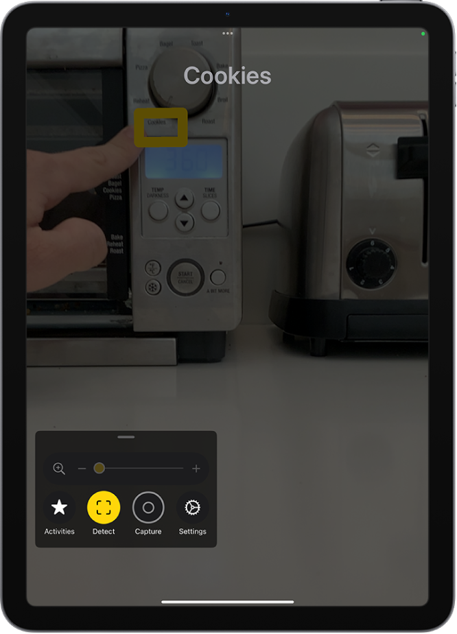 Lupe-appen som registrerer en finger som peker på tekst på et kjøkkenapparat.