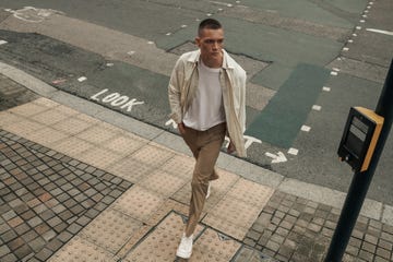 person walking on a sidewalk near a street with a pedestrian crossing signal