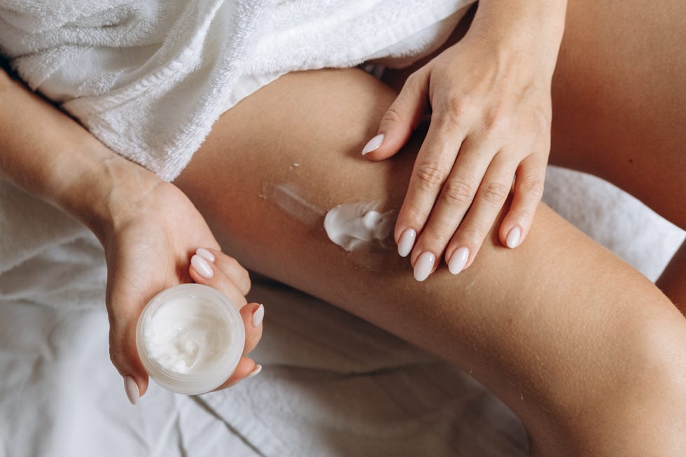 a woman applies moisturizing or anti cellulite or anti aging cream to the skin of her thighs, daily skin care after a shower