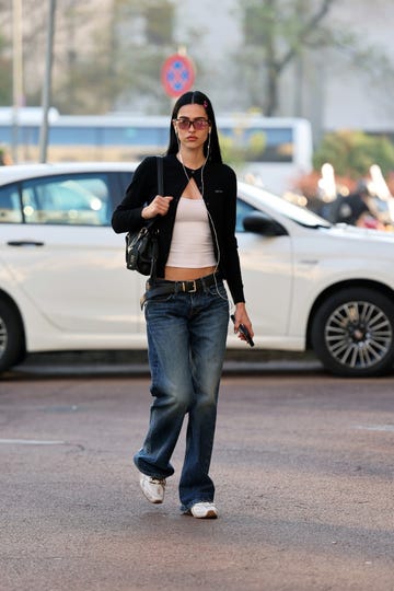 a person walking on a street with a background of parked vehicles