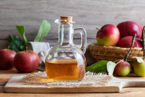 a bottle of apple cider vinegar with fresh apples