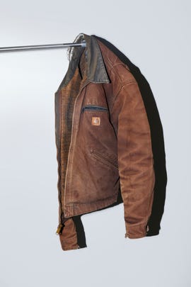 brown work jacket hanging on a metal rail