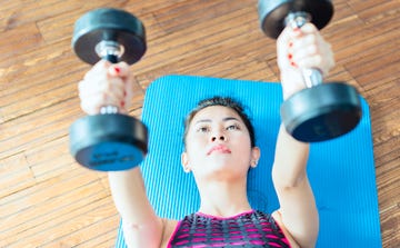 female fitness instructor working out, doing bench press with dumbbells in health club