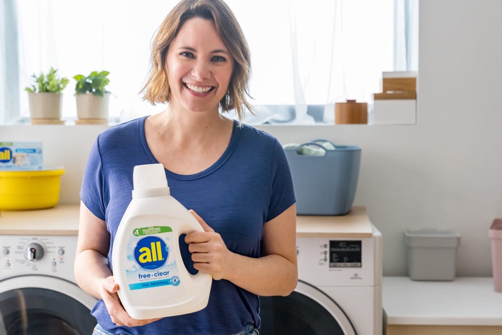 woman holding all free clear laundry detergent bottle