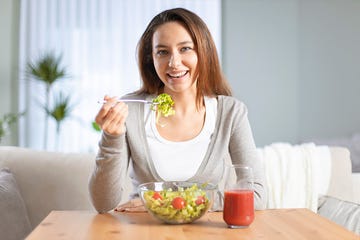 portrait of an attractive young woman eating a salad in living roomn