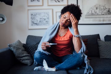 worried african american woman sitting at home while being sick