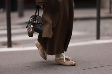 paris, france september 29 anna wein is seen wearing an ankle length brown wool trench coat paired with a wide long scarf from sandro, a rectangular black leather bag with gold details and several bag charms from miu miu, beige socks, and beige sneakers with fluffy lining and two different shoelaces in cream white cotton and brown leather from miu miu x new balance during paris fashion week on september 29, 2024 in paris, france photo by jeremy moellergetty images