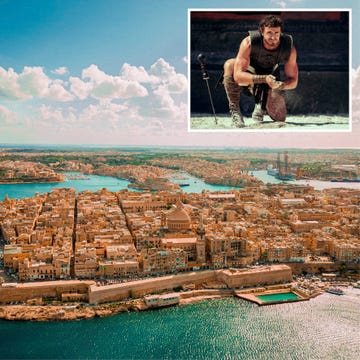 aerial view of a coastal city with historic architecture and a small inset image of a gladiator kneeling