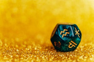 glowing green divination dice aquarius on gold colored background