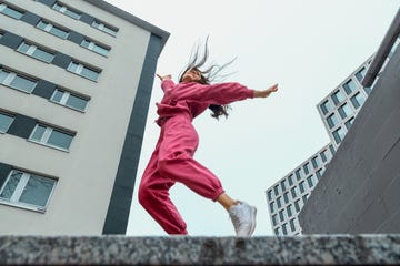 happy woman with arms raised and tousled hair, low angle view