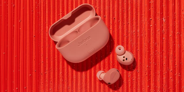 wireless earbuds and their charging case in a pink color on a textured red background