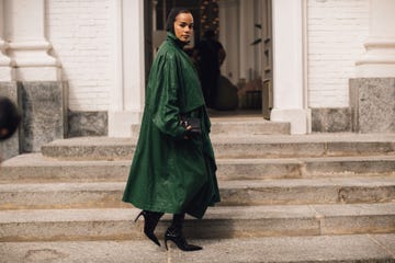 person wearing a green coat and high heels walking down stairs