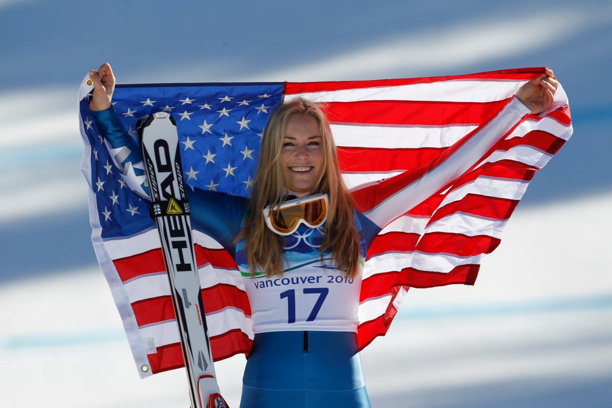 lindsey vonn holds up the american flag after winning bronze in the 2010 olympics