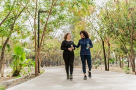 mother and daughter talking and walking through a public park