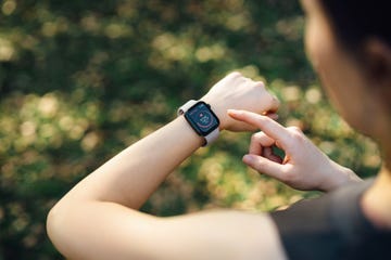 over the shoulder view of young asian sports woman resting after working out outdoors in green park, measuring heart rate on her smartwatch health and fitness training with technology wearable technology healthy living lifestyle, sports routine concept