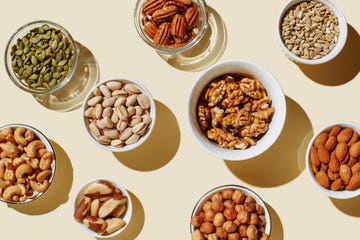 various nuts in white bowls on a beige display