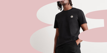 black tshirt worn by a model against a soft pink background