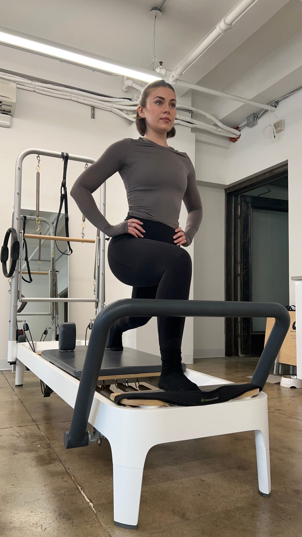 women's health fitness editor and writer talene appleton testing the allegro 2 pilates reformer machine in her apartment for at home pilates workouts