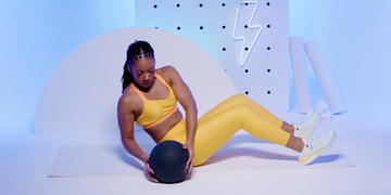 a fitness trainer performing the slam ball russian twist, a functional core exercise