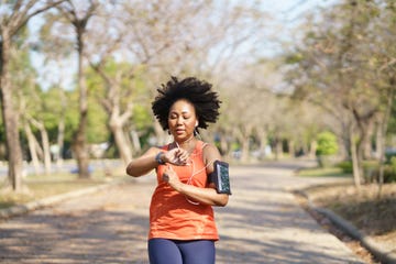 young black woman use fitness tracker on smartwatch tracking abilities heart rate, blood oxygen while running exercise at park