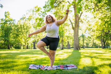 young woman practicing yoga outdoors in park