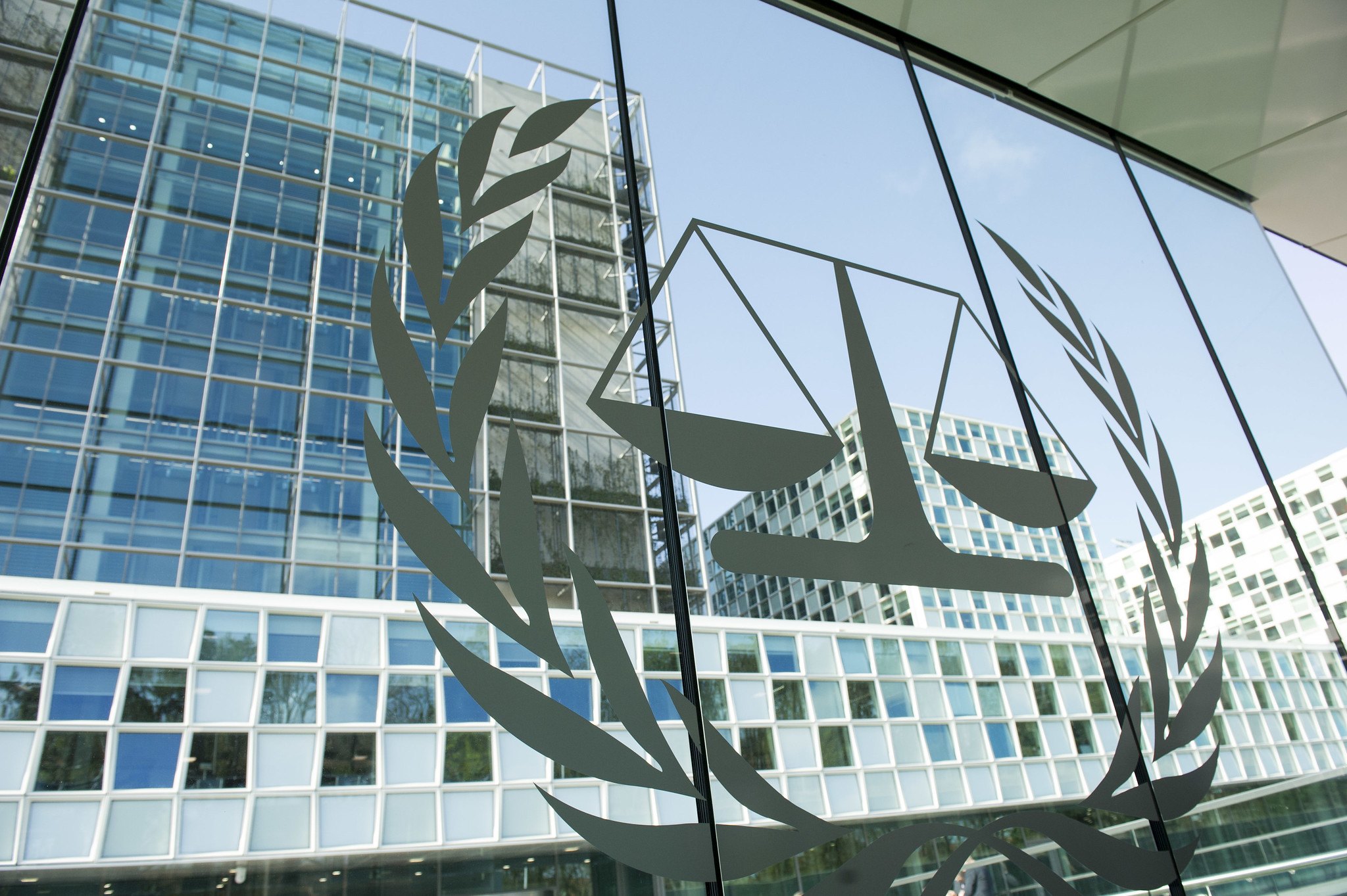 An illustration of two scales and a circular olive branch are seen on a window of a building.