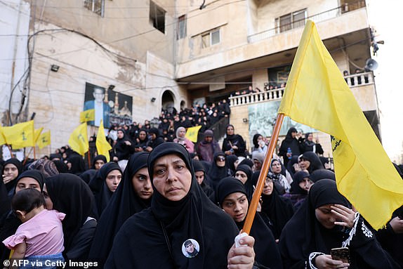 A woman carries a Hezbollah flag during the funeral of persons killed when hundreds of paging devices exploded in a deadly wave across Lebanon the previous day, in Beirut's southern suburbs on September 18, 2024. Hundreds of pagers used by Hezbollah members exploded across Lebanon on September 17, killing at least nine people and wounding around 2,800 in blasts the Iran-backed militant group blamed on Israel. (Photo by ANWAR AMRO / AFP) (Photo by ANWAR AMRO/AFP via Getty Images)