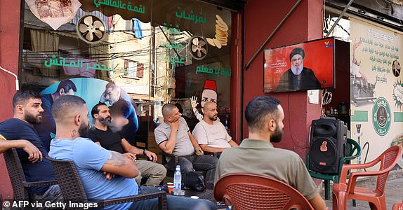 People watch on a television screen Hezbollah leader Hassan Nasrallah as he addresses the nation via video link, at a cafe in the Shiyah neighbourhood of Beirut's southern suburbs on September 19, 2024. Nasrallah said during his speech that Israel had dealt an "unprecedented" blow to his group, crossing all red lines with device explosions that killed 37 people and wounded nearly 3,000 over two days. (Photo by ANWAR AMRO / AFP) (Photo by ANWAR AMRO/AFP via Getty Images)