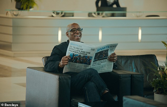 The former England striker, who scored 185 goals for the Gunners, is filmed reading a newspaper inside a reception area at Canary Wharf when he greets the 7ft Arsenal stalwart