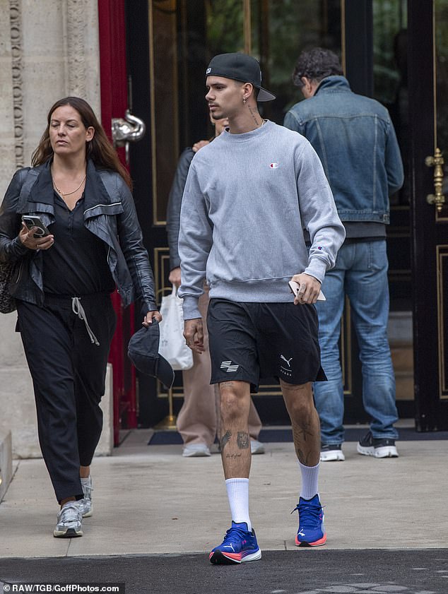 He sported a black baseball cap, which he wore backwards, and completed his look with a silver chain necklace and cross diamond encrusted earrings