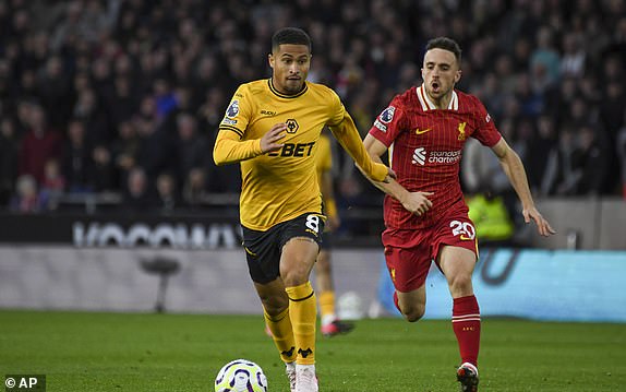 Wolverhampton Wanderers' Joao Gomes, center, is chased by Liverpool's Diogo Jota during the English Premier League soccer match between Wolverhampton Wanderers and Liverpool at the Molineux Stadium in Wolverhampton, England, Saturday, Sept. 28, 2024. (AP Photo/Rui Vieira)