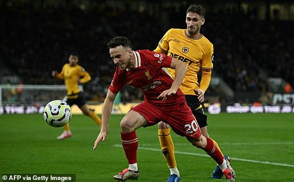 Wolverhampton Wanderers' Uruguayan defender #04 Santiago Bueno (R) fouls Liverpool's Portuguese striker #20 Diogo Jota during the English Premier League football match between Wolverhampton Wanderers and Liverpool at the Molineux stadium in Wolverhampton, central England on September 28, 2024. (Photo by Paul ELLIS / AFP) / RESTRICTED TO EDITORIAL USE. No use with unauthorized audio, video, data, fixture lists, club/league logos or 'live' services. Online in-match use limited to 120 images. An additional 40 images may be used in extra time. No video emulation. Social media in-match use limited to 120 images. An additional 40 images may be used in extra time. No use in betting publications, games or single club/league/player publications. /  (Photo by PAUL ELLIS/AFP via Getty Images)