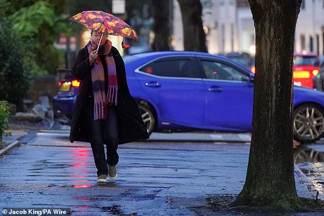 A woman holds an umbrella during a rain shower in Warwick, after showery weather in Britain