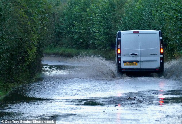 Vehicles drive down the water logged country lanes at first light in Dunsden, Oxfordshire, this morning