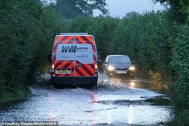 Cars travel through flooded country lanes this morning in Dunsden, Oxfordshire