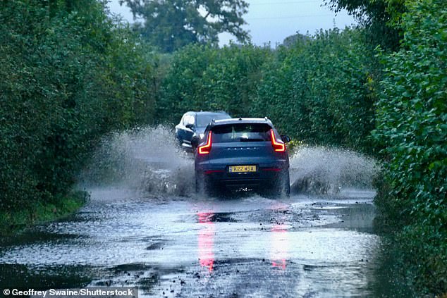 Vehicles drive down the water logged country lanes at first light in Dunsden, Oxfordshire