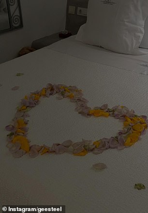 She hinted at the romantic trip as she shared a photo of their hotel room bed covered in a love heart made of rose petals