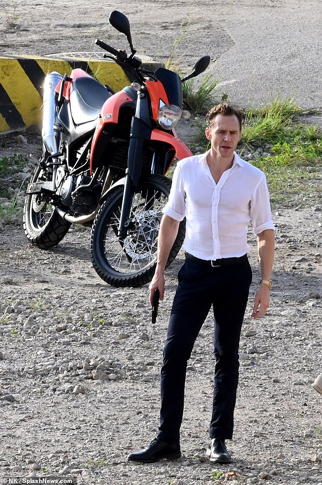 Tom Hiddleston poses in front of a motorbike as he appears on set of The Night Manager