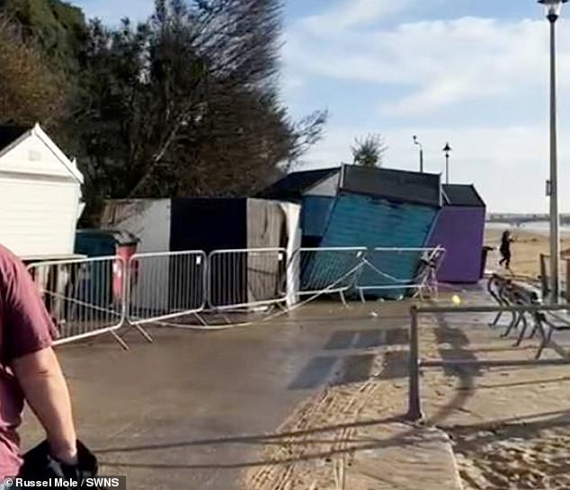 Footage shows a woman (right) narrowly escaping being hit by a landslide as cliffs fall onto beach huts