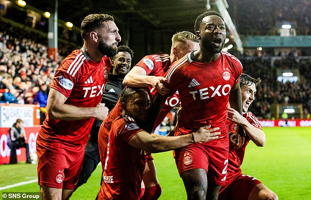 Morris celebrates with delirious team-mates as the Dons' incredible season continues apace