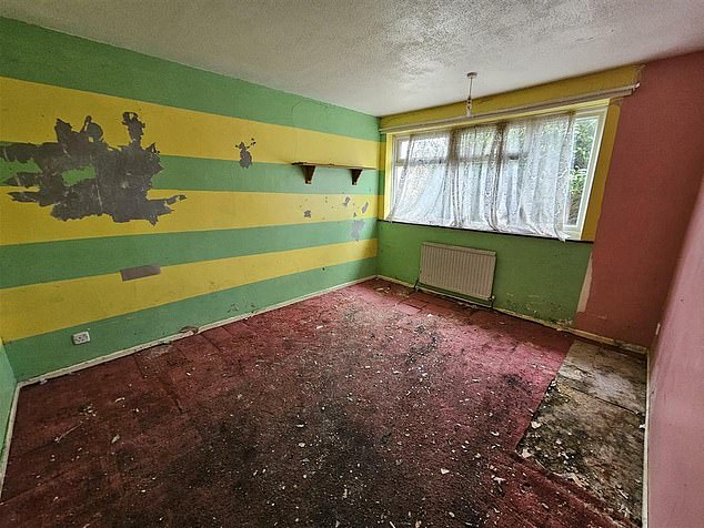 One of the bedrooms has some damage to the striped wallpaper and the floor is covered in dirt