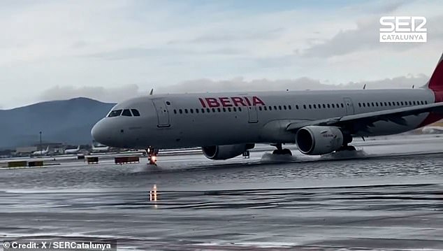 An Iberia airlines plane ploughs through floodwaters at El Prat airport this morning