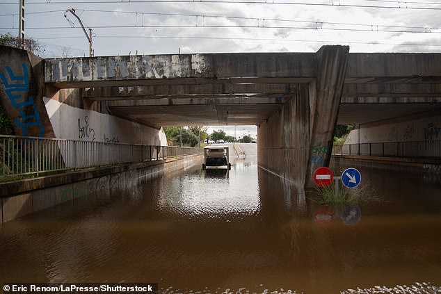 A lorry is seen submerged in high floodwater under a bridge near Barcelona