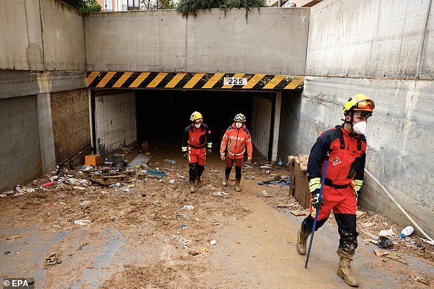 Firefighters walk past debris as they search for victims at a parking area on November 4