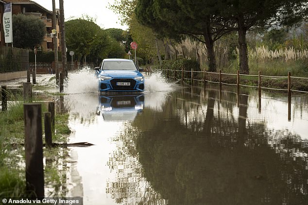 A vehicle drives through rain following floods in Castelldefels near Barcelona