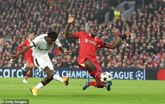 LIVERPOOL, ENGLAND - NOVEMBER 05: Jeremie Frimpong of Bayer 04 Leverkusen scores a goal whilst under pressure from Ibrahima Konate of Liverpool which is later is disallowed due to handball during the UEFA Champions League 2024/25 League Phase MD4 match between Liverpool FC and Bayer 04 Leverkusen at Anfield on November 05, 2024 in Liverpool, England. (Photo by Carl Recine/Getty Images)