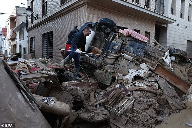 A man walks over debris to access a street in a mud-covered street in the flood-hit city of Paiporta, Valencia, Spain, November 7, 2024